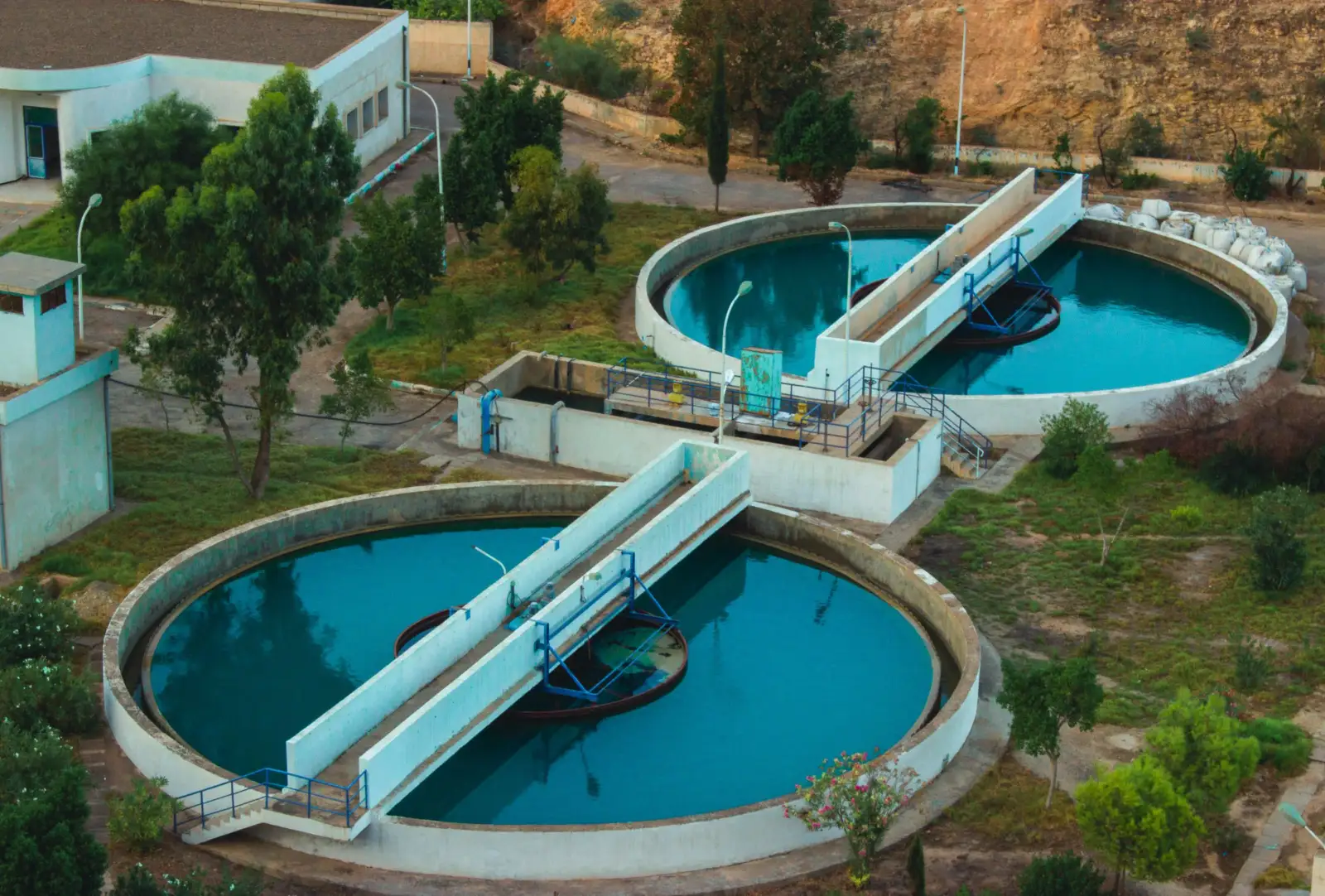 Bassins circulaires d'une station de traitement d'eau vus du ciel, entourés d'arbres