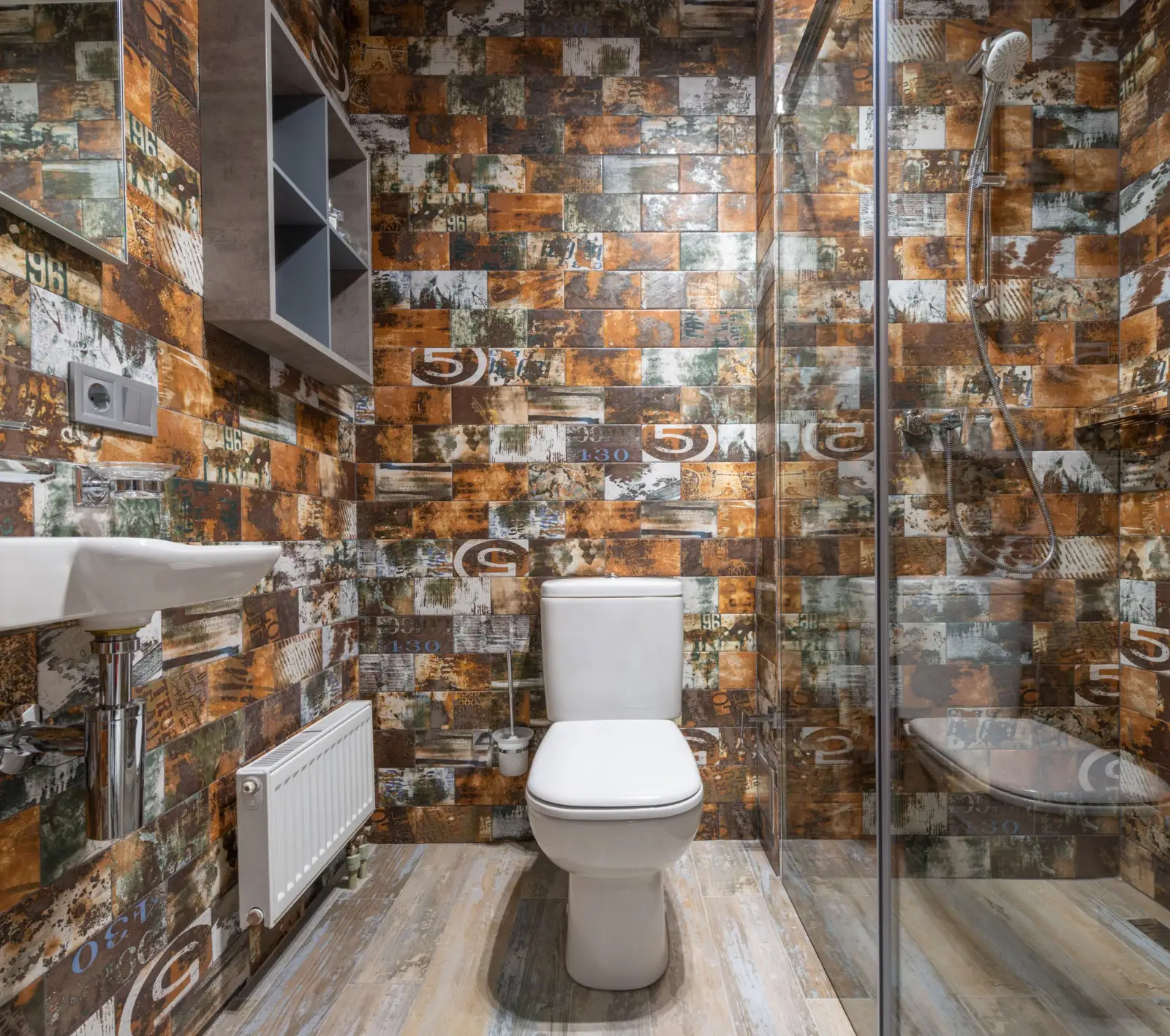 WC à poser blanc avec réservoir attenant dans des toilettes carrelées, à côté d'une douche vitrée