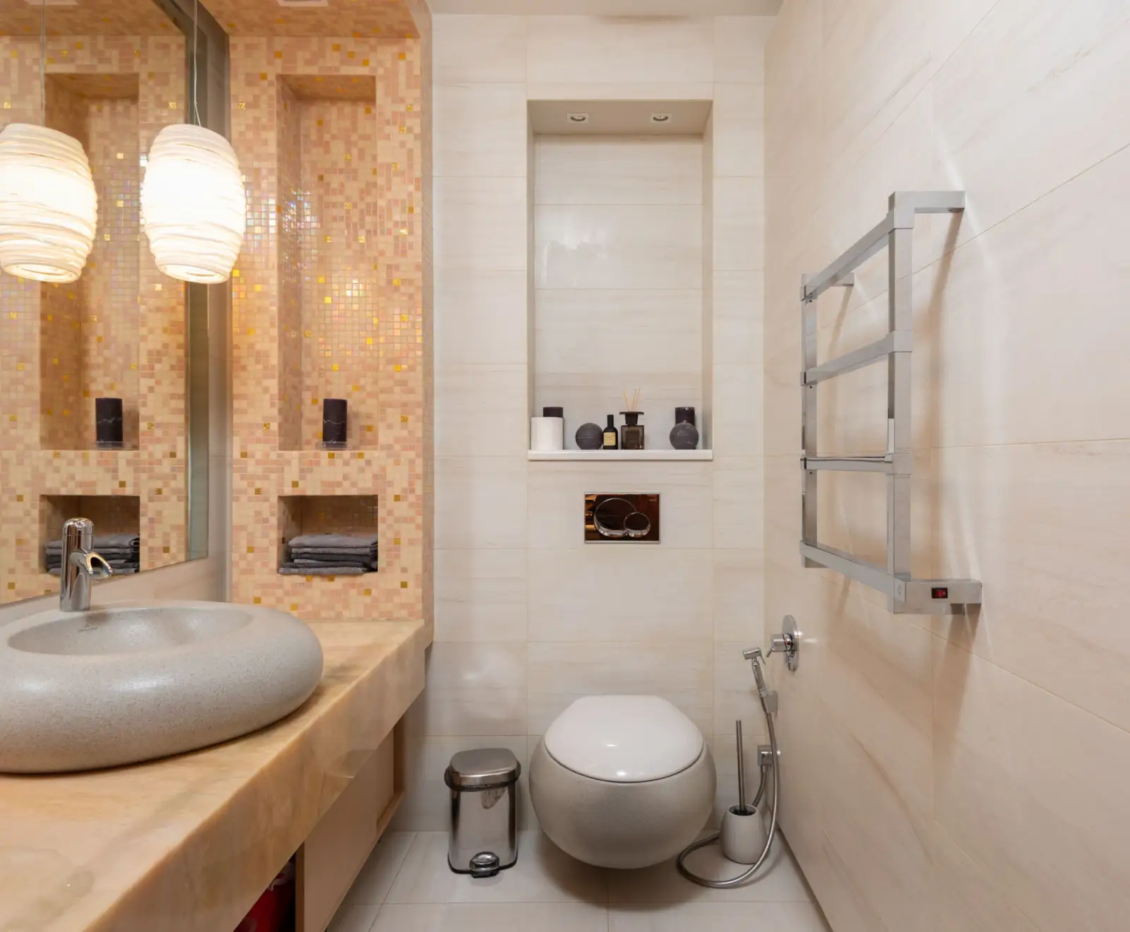 Petite salle de bain avec WC suspendu blanc, plaque de commande murale au-dessus, douchette d'hygiène et sèche-serviettes